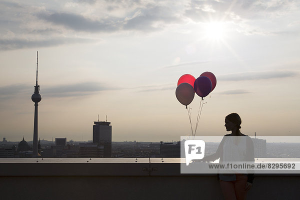 Young woman on rooftop terrace  holding balloons