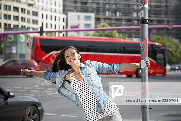 Young women in the city  holding onto pole