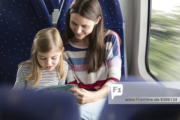 Mother and daughter reading book in a train