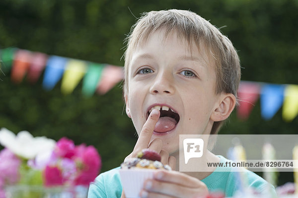 Glücklicher Junge beim Muffinessen auf einer Geburtstagsfeier