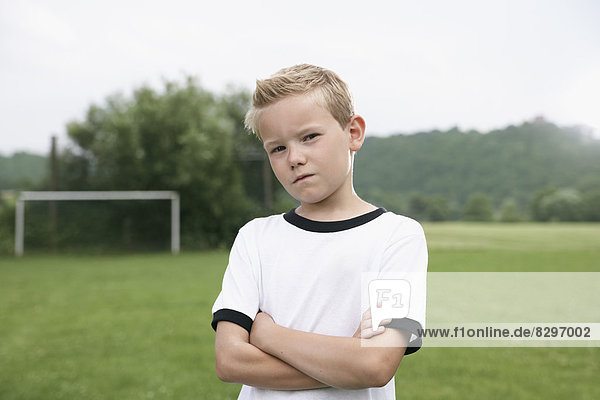 Zuversichtlicher Junge im Fußballtrikot auf dem Fußballplatz