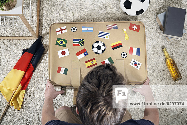 Soccer fan with national flags on suitcase