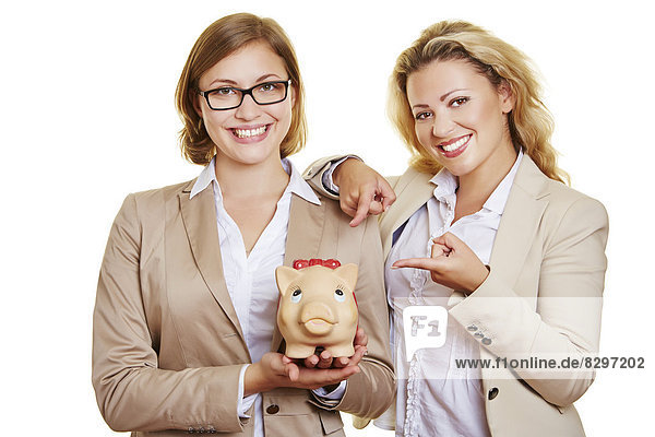 Zwei Geschäftsfrauen halten Sparschwein  lächelnd