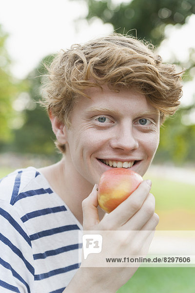 Young man eating an apple outdoors