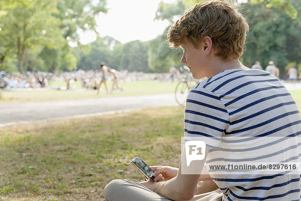 Young man with cell phone in park