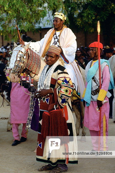 A n honoured chief riding a decorated horse with his attendants at a Durbar in Maidugari  Nigeria