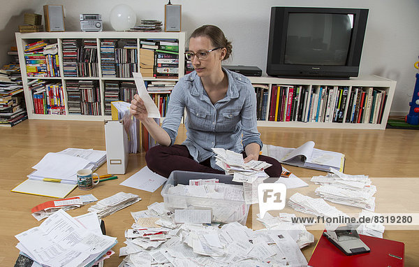 Woman sorting documents  records  invoices and receipts on the ground  for the tax return