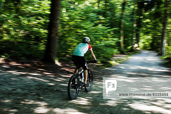 Frau fährt mit Mountainbike auf Forstweg im Feldafinger Park
