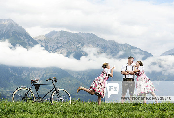 Man and a woman wearing traditional costume with an old bicycle within a natural landscape  photocomposing