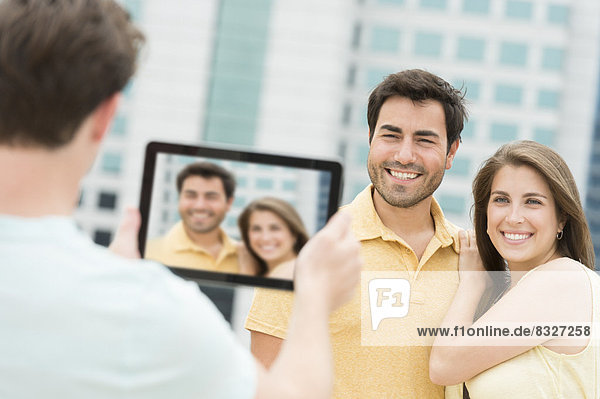 Man using tablet pc to take picture of friends