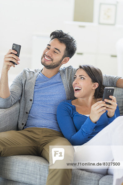 Couple relaxing on sofa with cell phones