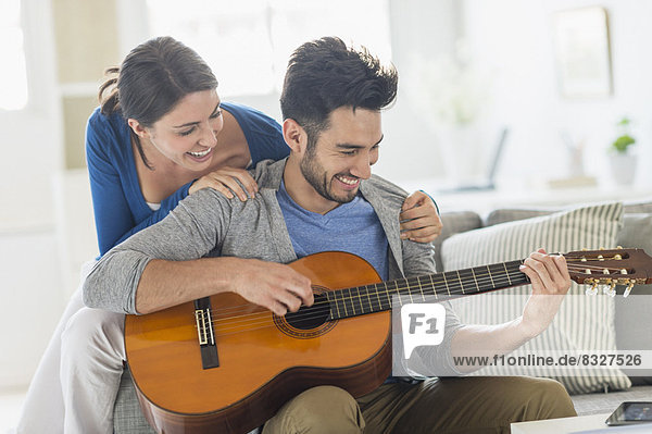 Man playing guitar while woman embracing him