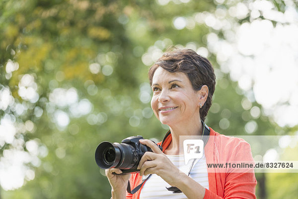 Mature woman holding camera in park