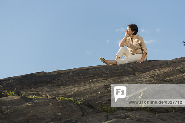 Mature woman sitting on rock
