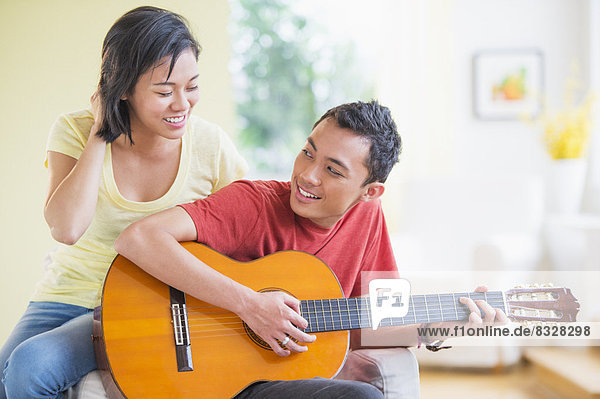 Young man playing guitar  woman listening