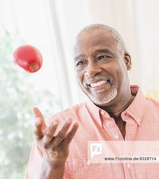 Portrait of man throwing red apple
