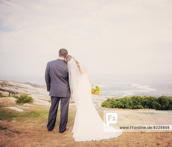Rear view of married couple standing by sea