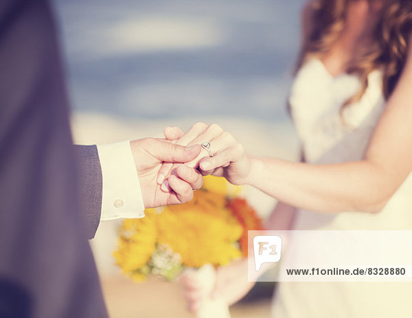Close up of bride and groom holding hands