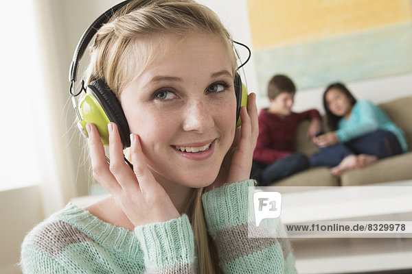 Girl (14-15) listening to music wearing headphones