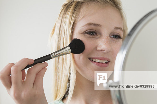 Girl (14-15) applying make up