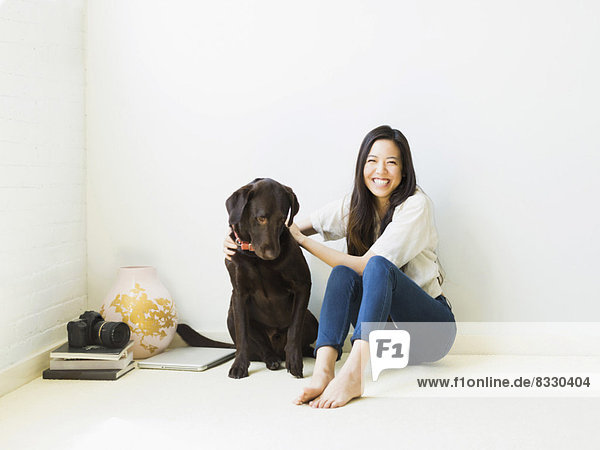 Portrait of woman with dog sitting on floor