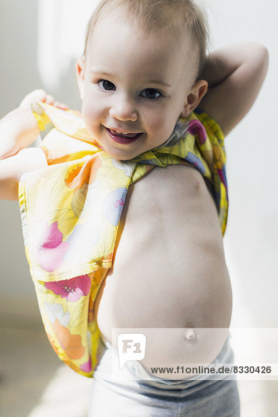 Portrait of girl (12-17 months) showing bellybutton