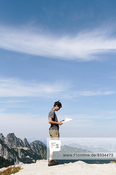 Ein Wanderer auf dem Berggipfel  der auf eine Karte schaut. Überraschungsberg  Alpine Lakes Wilderness  im Mount Baker-Snoqualmie National Forest