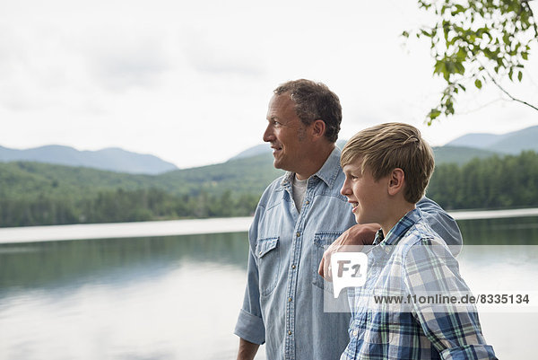 A family outdoors under the trees on a lake shore. Father and son.