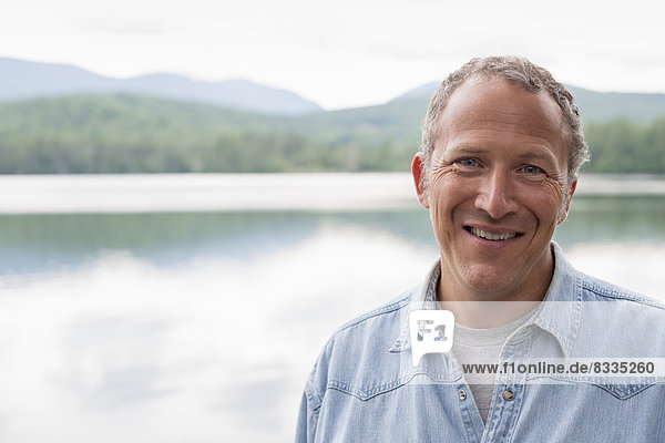 A man on the shore of a lake in New York state.