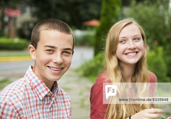 Zwei junge Menschen  Junge und Mädchen sitzen nebeneinander und lachen.