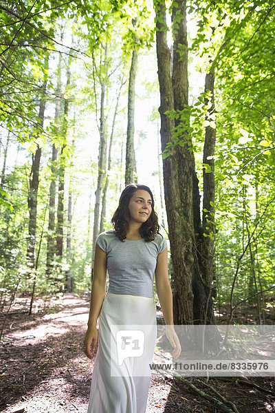 A young woman walking through woodland.