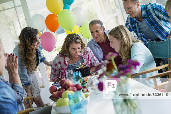 Eine Geburtstagsfeier in einer Bauernküche. Eine Gruppe von Erwachsenen und Kindern versammelte sich um einen Schokoladenkuchen.