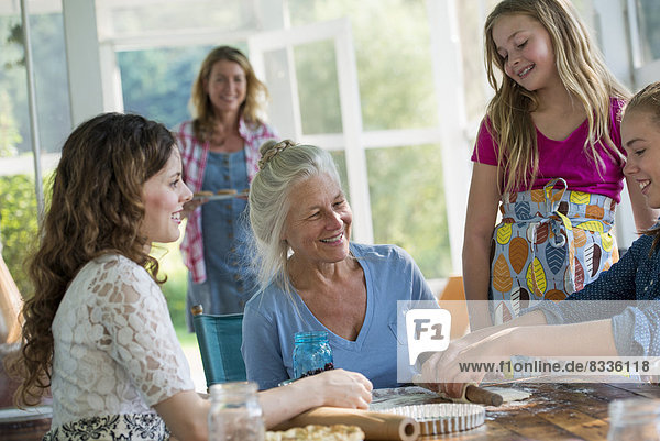 Farmhouse in the country in New York State. Four generations of women in a family baking together.