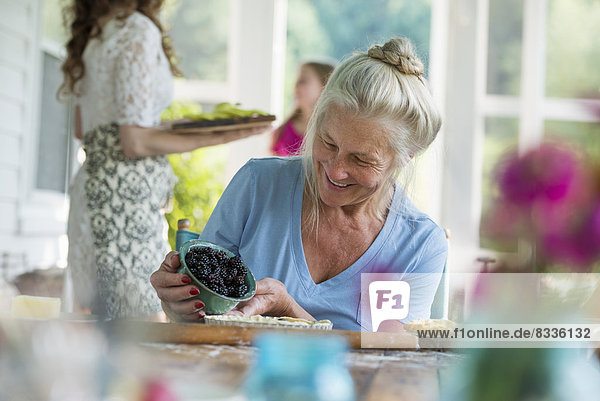 A family party in a farmhouse in the country in New York State. A mature woman holding bowl of fresh blackberries.