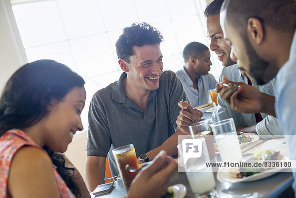 Eine Gruppe von Männern und Frauen in einem Café  die etwas trinken und die Gesellschaft des anderen genießen.