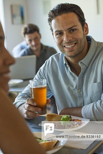 Eine Gruppe von Männern und Frauen in einem Café  die essen und trinken und die Gesellschaft des anderen genießen.