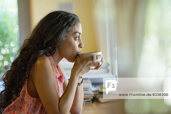 Eine Frau  die allein in einem Café sitzt und Kaffee trinkt.