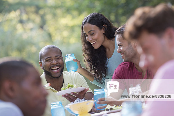 Eine Gruppe von Menschen  die unter freiem Himmel eine Mahlzeit einnimmt  ein Picknick. Männer und Frauen.