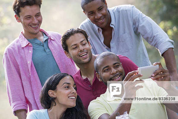 Eine Gruppe von Menschen  die unter freiem Himmel eine Mahlzeit einnimmt  ein Picknick. Männer und Frauen.