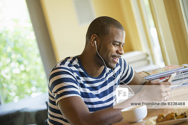 A man sitting in a cafe  having a cup of coffee  listening to music with headphones.