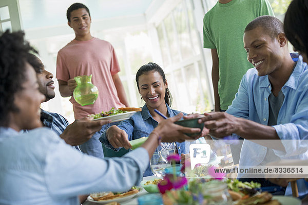 Eine Gruppe von Frauen und Männern um einen Tisch  die in einer Bauernküche eine Mahlzeit teilen.