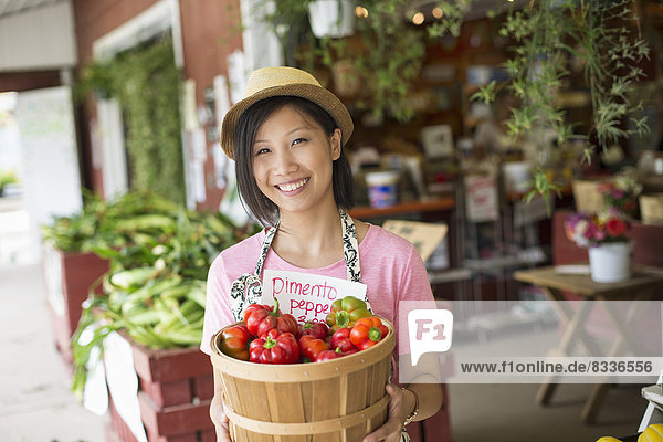 Eine Frau  die an einem Stand eines Biobetriebs arbeitet und frisches Gemüse zum Verkauf anbietet.
