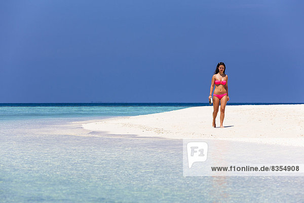 Woman with a book walking along the beach  Male  North Male Atoll  Maldives