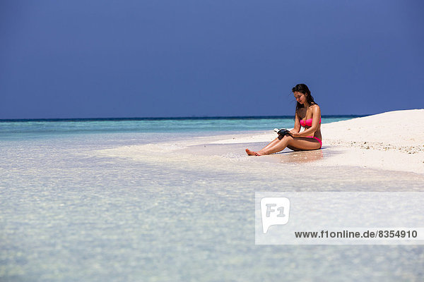 Woman with a book sitting on the beach  Male  North Male Atoll  Maldives