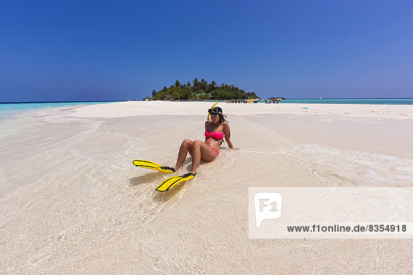 Woman with flippers and diving goggles  sitting on a sand bank  Indian Ocean  Maldives