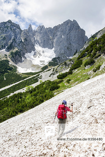 Female hiker crossing a snowfield on the Wilder-Kaiser-Steig hiking trail  Kaisergebirge  near Ellmau  Tyrol  Austria