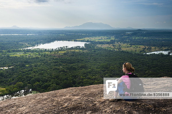 Woman sitting on Pidurangala Rock  looking at the jungle landscape of North Central Province  Sri Lanka  Asia