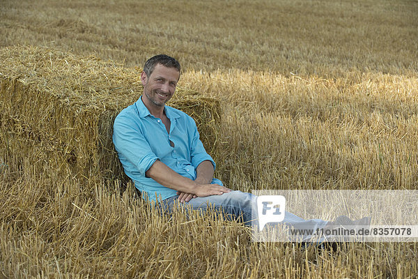 Man leaning against bale of straw