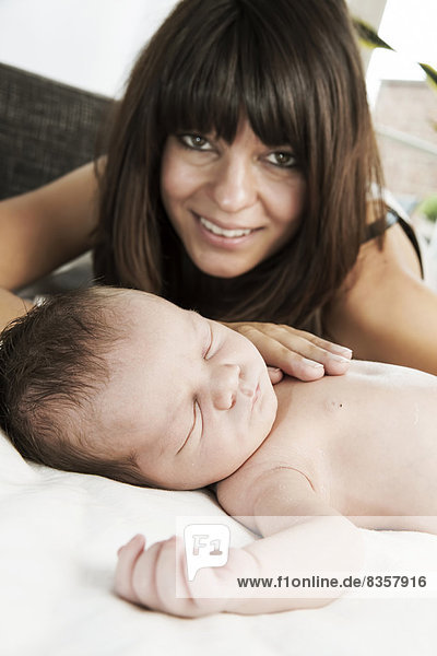 Smiling young mother and her sleeping newborn son
