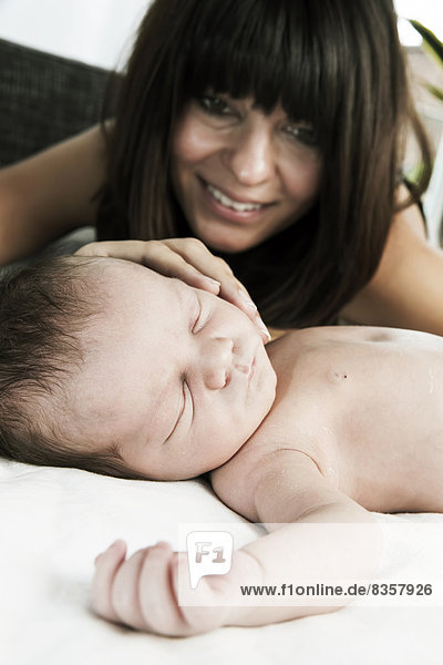 Lächelnde junge Mutter und ihr schlafender neugeborener Sohn